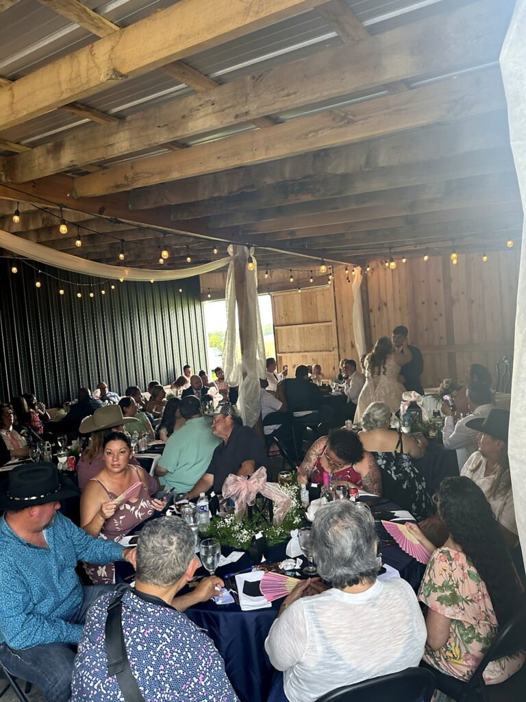 Princeton Kentucky Wedding DJ 7 Guests seated at tables in a rustic barn during a wedding reception, with a bride and groom dancing in the background
