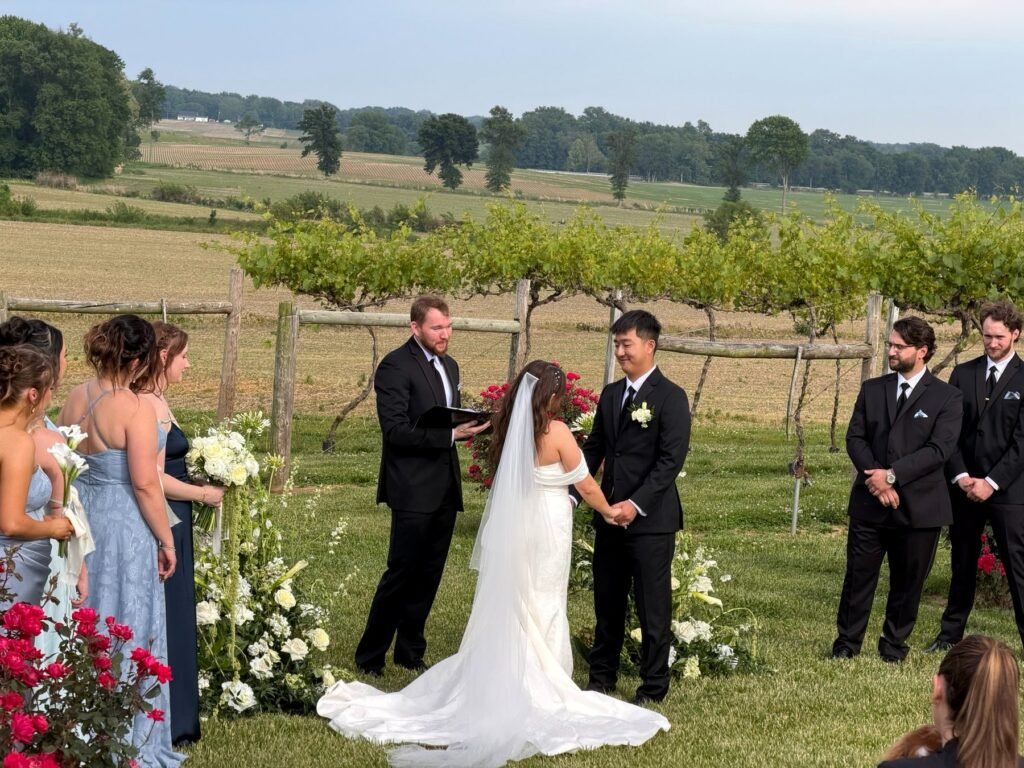 Bride and groom hold hands during a vineyard wedding ceremony at Farmer & Frenchman near Henderson, KY