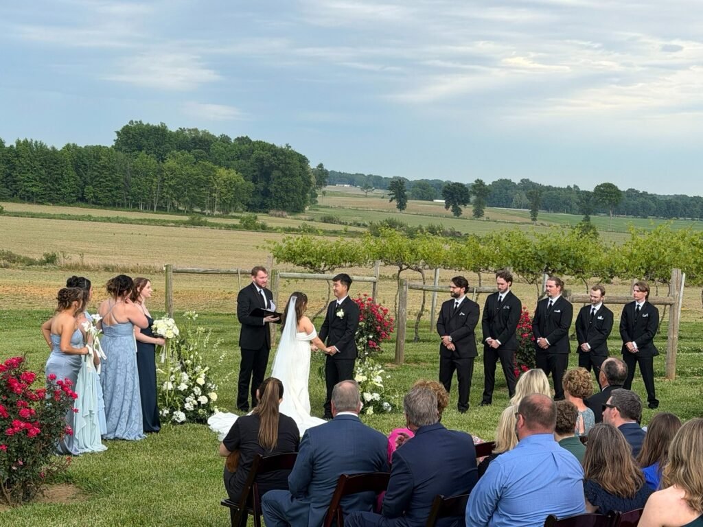 Wide view of an outdoor wedding ceremony with the wedding party and guests at Farmer & Frenchman near Henderson, KY