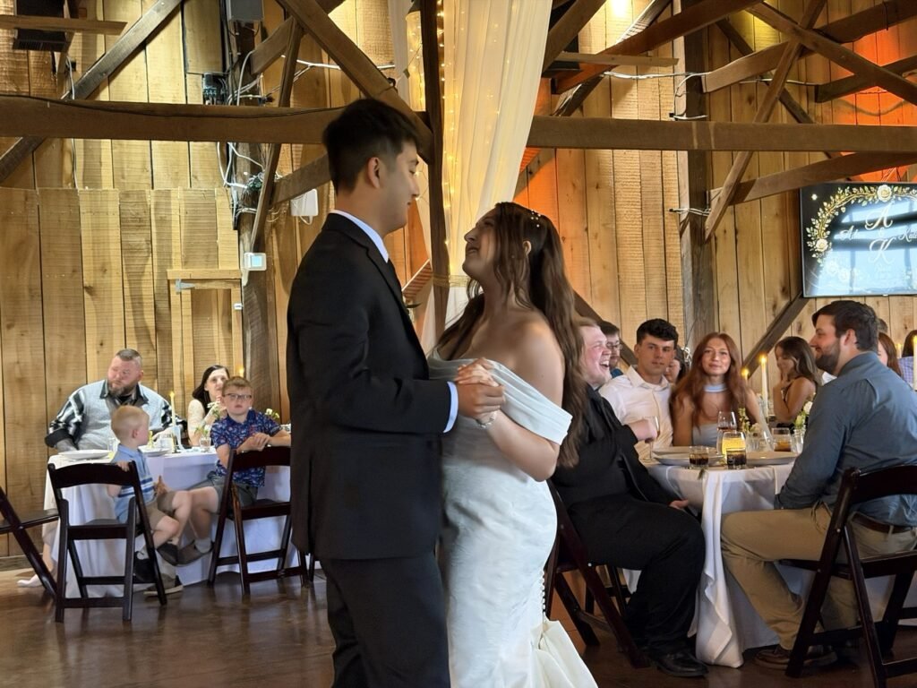 Newlyweds share a first dance in the barn at Farmer & Frenchman as guests watch, near Henderson, KY