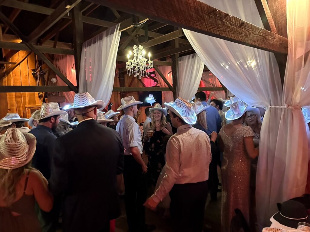 Wedding guests wearing light-up silver cowboy hats in the Farmer & Frenchman barn near Henderson, KY