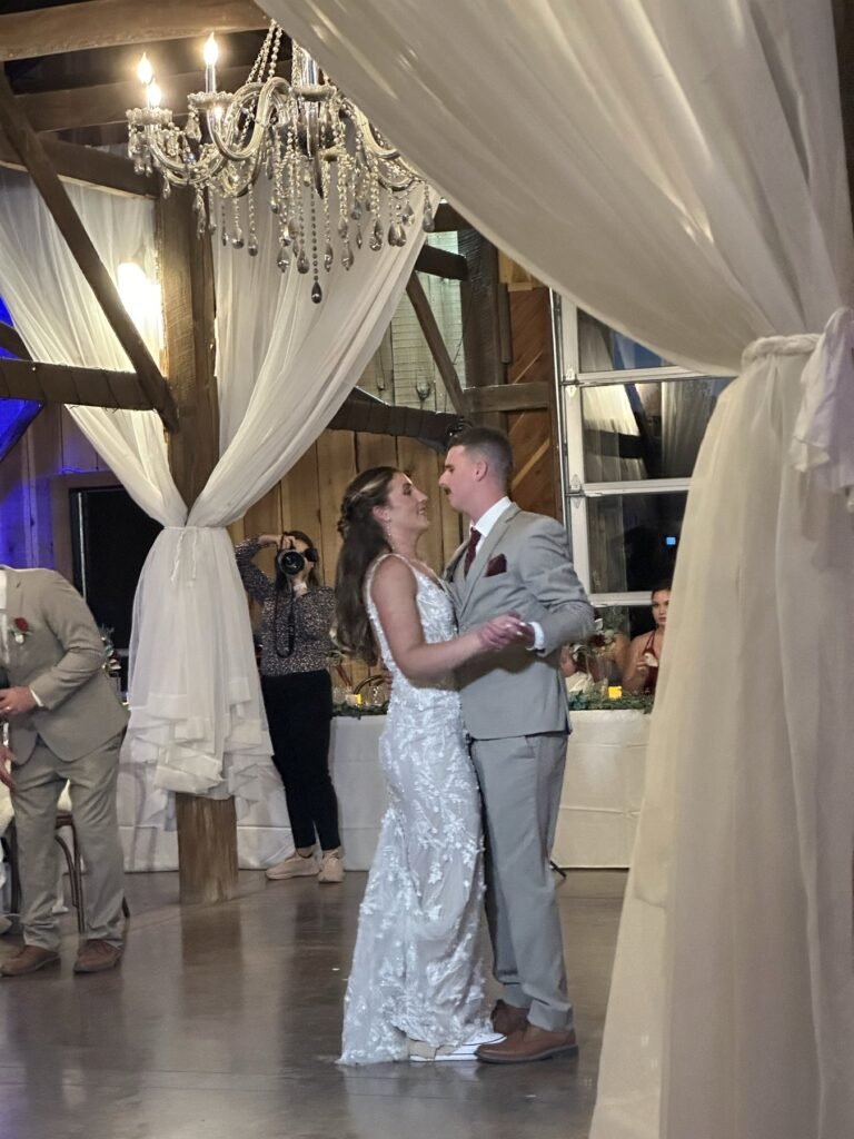 Bride and groom dance under a crystal chandelier in the Farmer & Frenchman barn near Henderson, KY