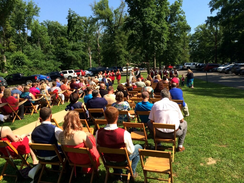 Guests seated in wooden chairs on a grassy lawn for an outdoor wedding ceremony