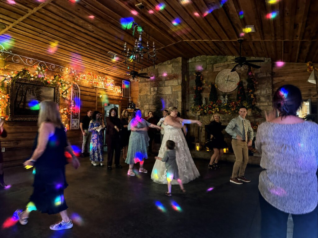 Princeton Kentucky Wedding DJ 11 A bride and guests dance in a rustic room with wood walls and colorful disco lights