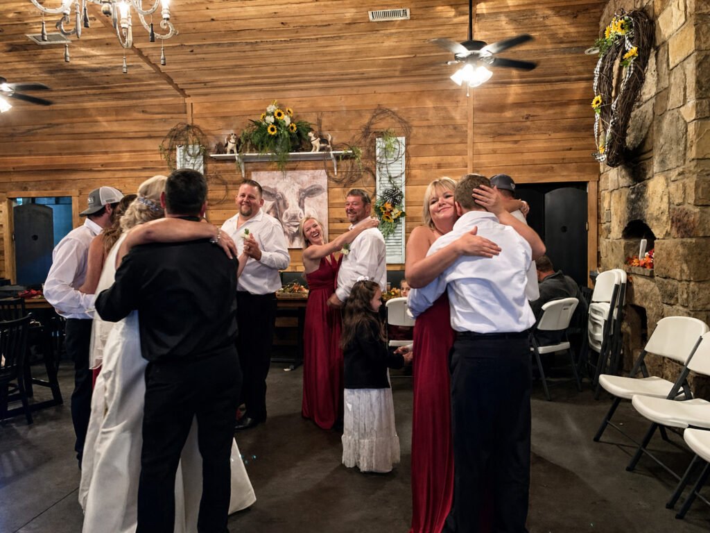 Princeton Kentucky Wedding DJ 15 Wedding guests and family in formal attire hugging and celebrating in a rustic wood-paneled room