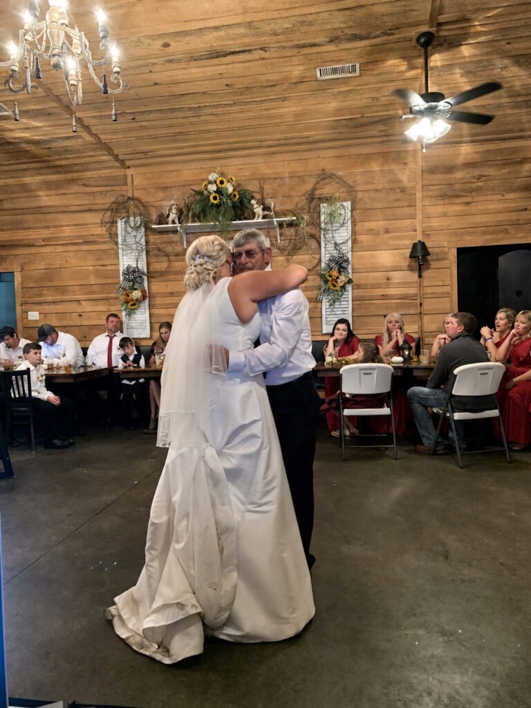 Princeton Kentucky Wedding DJ 17 Bride in a white wedding dress hugging a man in a rustic wood-paneled room with guests watching