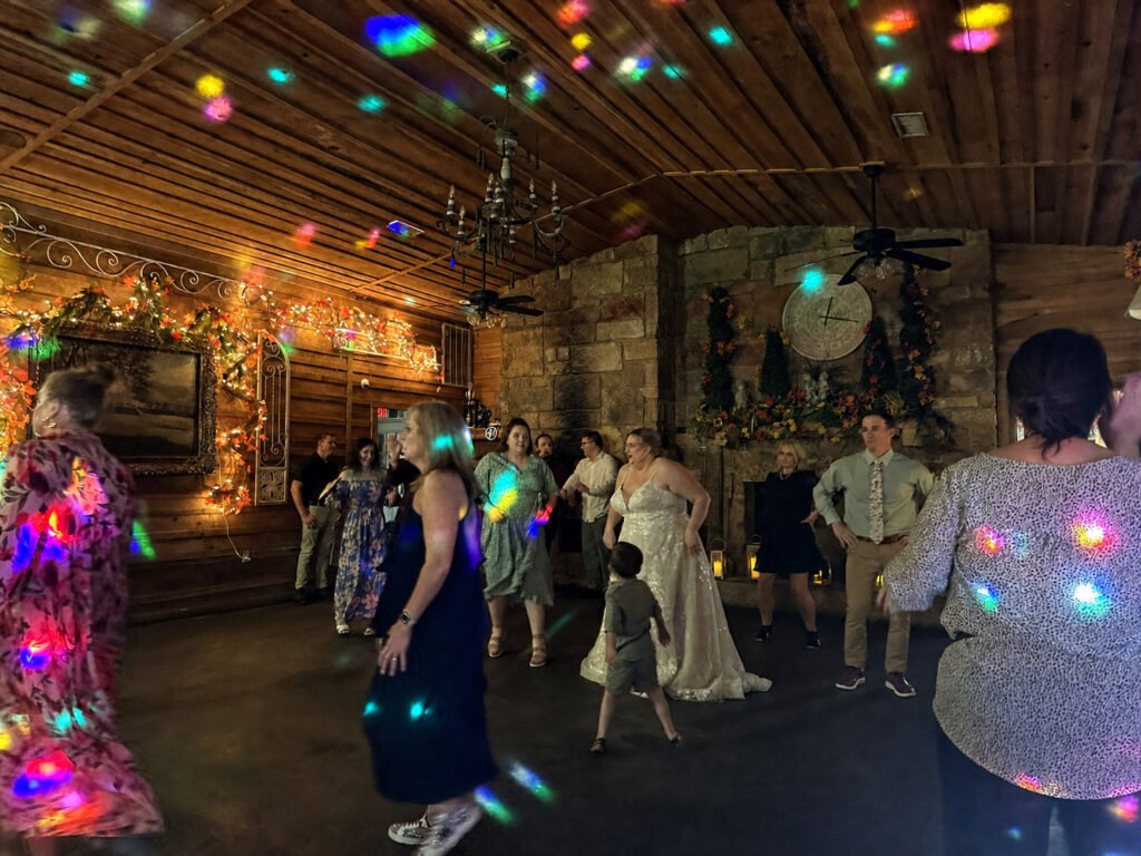 Princeton Kentucky Wedding DJ 16 Guests and a bride in a white gown dance in a rustic room illuminated by colorful disco lights
