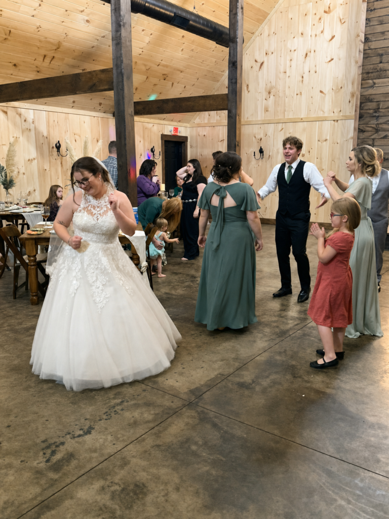 A bride in a white wedding dress dances with guests in a rustic wood-paneled reception hall