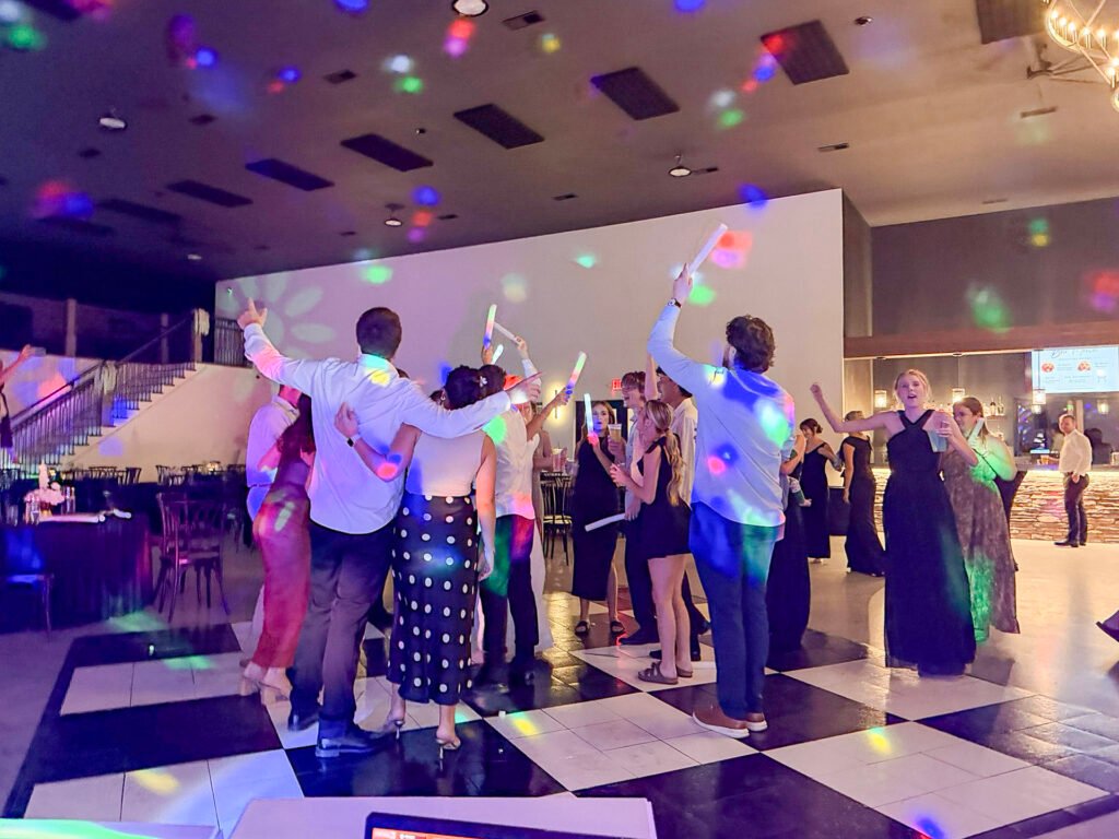Guests dancing on the checkered dance floor with glow sticks at a Highbanks wedding.