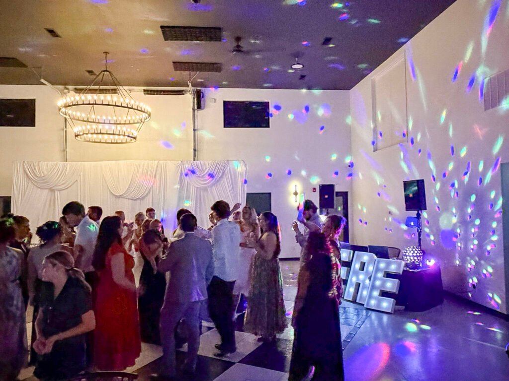 Guests dancing under the chandelier and colored lighting in the reception room at Highbanks.