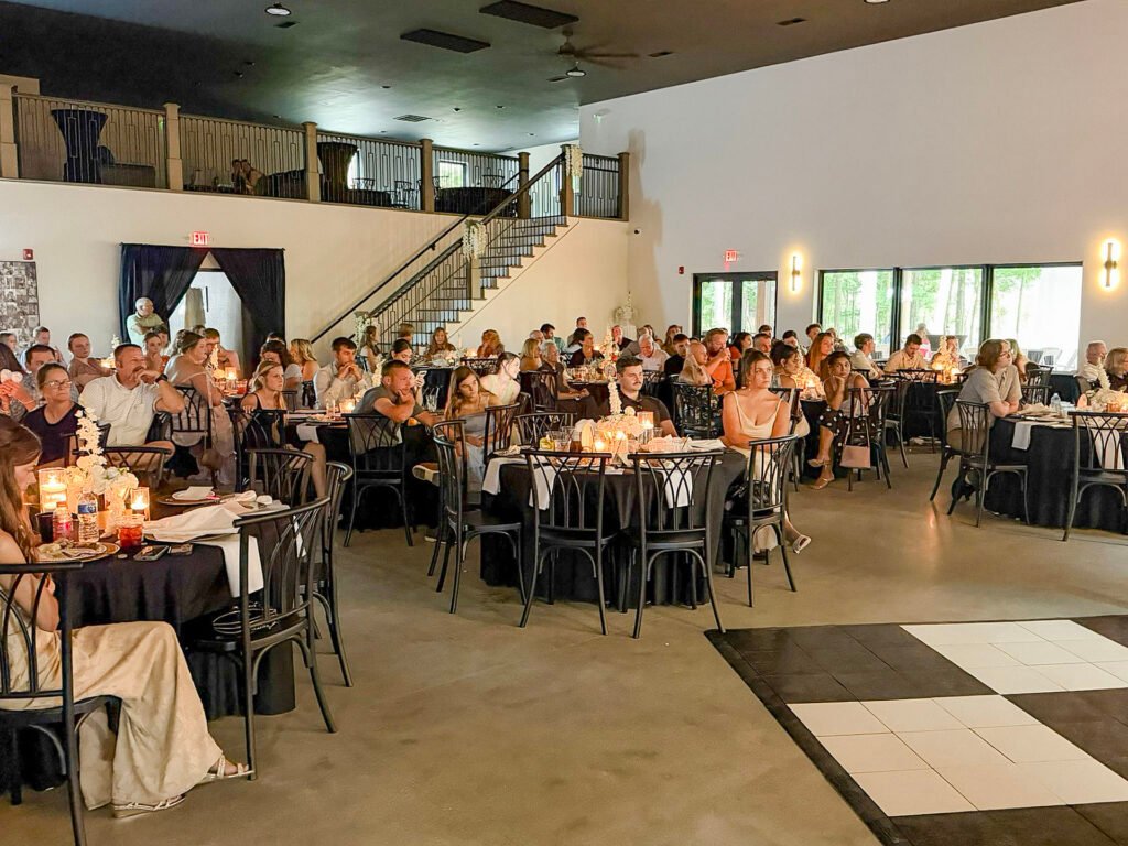 Guests seated at dinner tables in the large open reception room at Highbanks, beside the checkered dance floor.