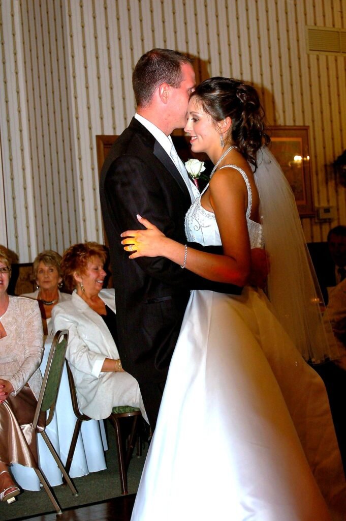 Madisonville Kentucky Wedding DJ 17 A groom in a tuxedo kisses the forehead of a bride in a white wedding dress as they dance together.